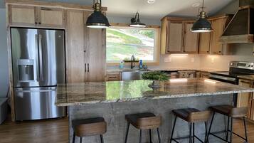 Une cuisine moderne avec des meubles en bois, des appareils en acier inoxydable et un grand îlot central doté de tabourets de bar.