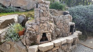 Une structure en pierre dotée de plusieurs ouvertures, entourée de gravier et de plantes.