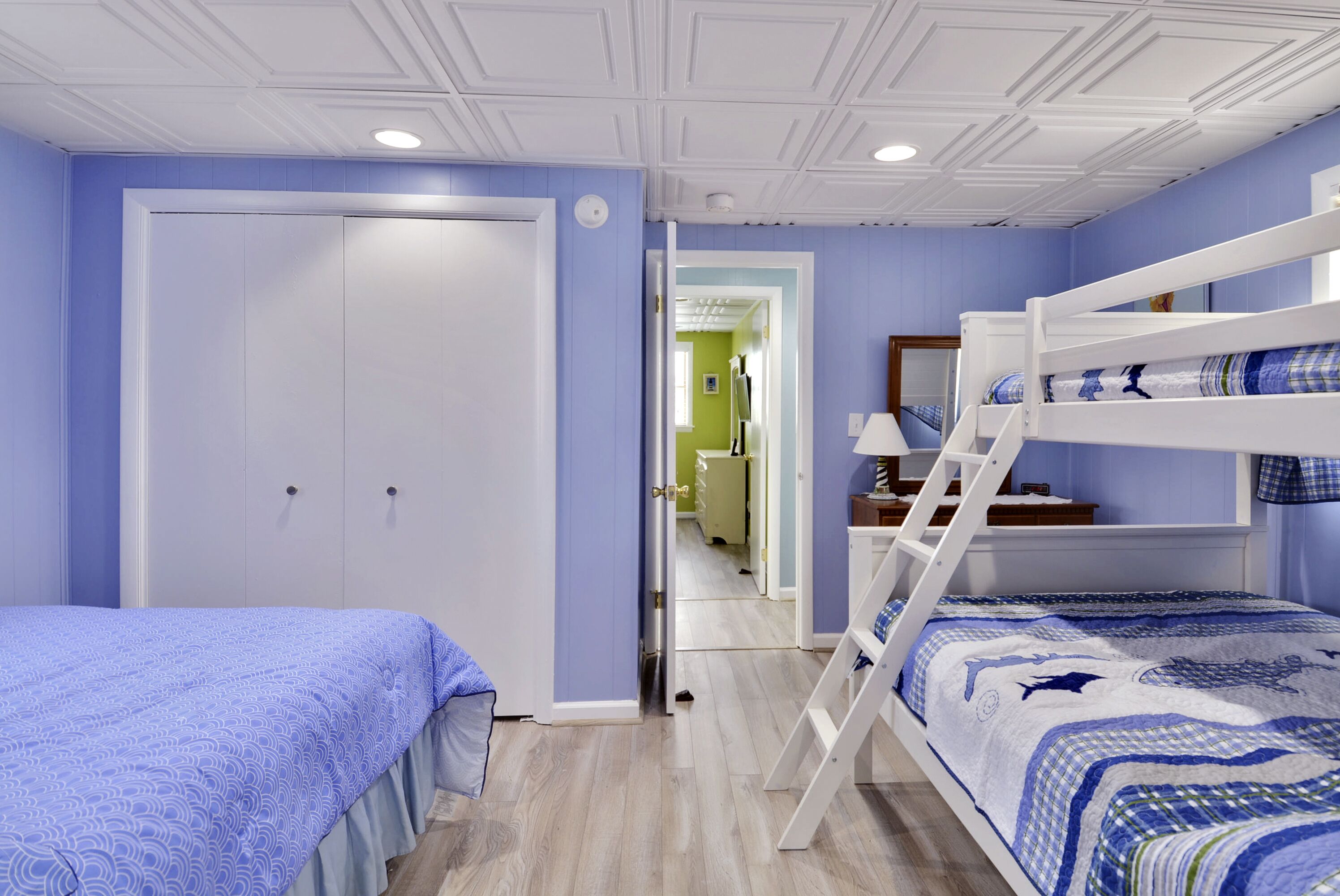 Ein Schlafzimmer mit Etagenbett, einer Tür und einem Flur, der zu einem Badezimmer führt.