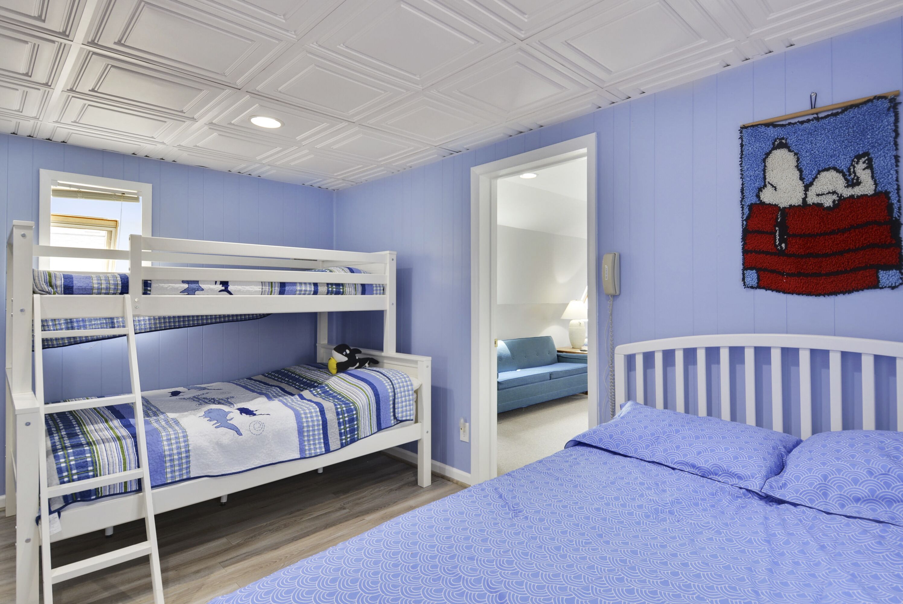 Quarto com beliches, parede azul, um espelho e um mural do Snoopy.