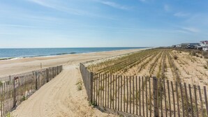 Ein Strand mit Holzzaun und blauem Himmel.