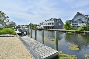 A waterfront property with a dock, a house with a balcony, and a boat docked nearby.