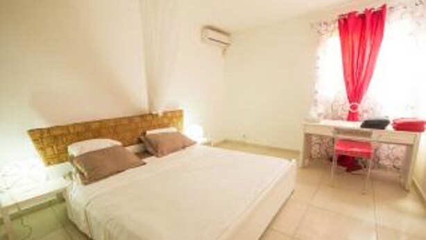 A bedroom with a bed, a bedside table, a desk, and a chair. - ABC HOME BEAUTY HEAT !!!!!!!!!!!!!!!! (Le Gosier)