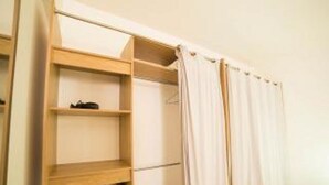A bedroom with a wooden wardrobe, a bed with a white duvet, and a curtain. - ABC HOME BEAUTY HEAT !!!!!!!!!!!!!!!! (Le Gosier)