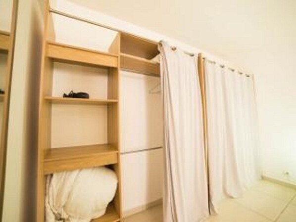 A bedroom with a wooden wardrobe, a bed with a white duvet, and a curtain. - ABC HOME BEAUTY HEAT !!!!!!!!!!!!!!!! (Le Gosier)