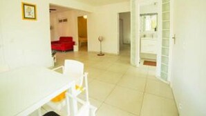 A bright, spacious room with a white table and chairs, a red sofa, and a door leading to another room. - ABC HOME BEAUTY HEAT !!!!!!!!!!!!!!!! (Le Gosier)