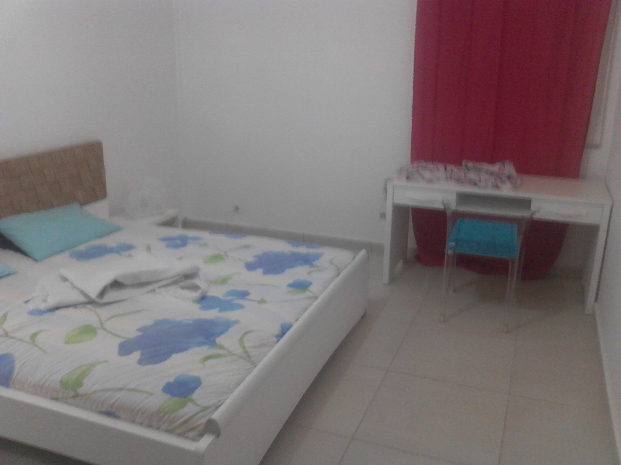 A bedroom with a bed, a desk, and a chair.