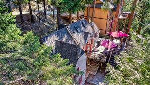 Eine Lodge mit einer Holzdachterrasse, einer überdachten Sitzgruppe im Freien und Blick auf den umliegenden Wald.