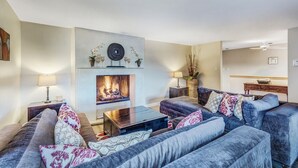 A living room with a fireplace, sofas, a coffee table, and a sideboard.