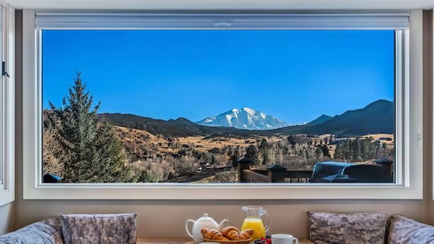 A breakfast setup with croissants, juice, and coffee on a table with a mountain view.