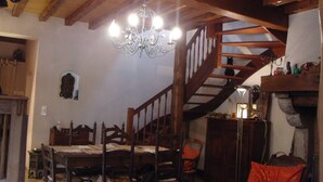 Un comedor con mobiliario de madera, un candelabro y una escalera.