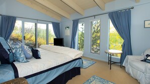 A bedroom with a bed, a TV, a chair, and large windows with curtains. - Luxury Family Retreat. Ski-in Ski-Out.  Spectacular Mountain Views.  Sleeps 12  (Snowmass Village)