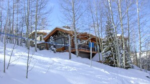 A snow-covered landscape with a wooden cabin and a ski lift. - Luxury Family Retreat. Ski-in Ski-Out.  Spectacular Mountain Views.  Sleeps 12  (Snowmass Village)