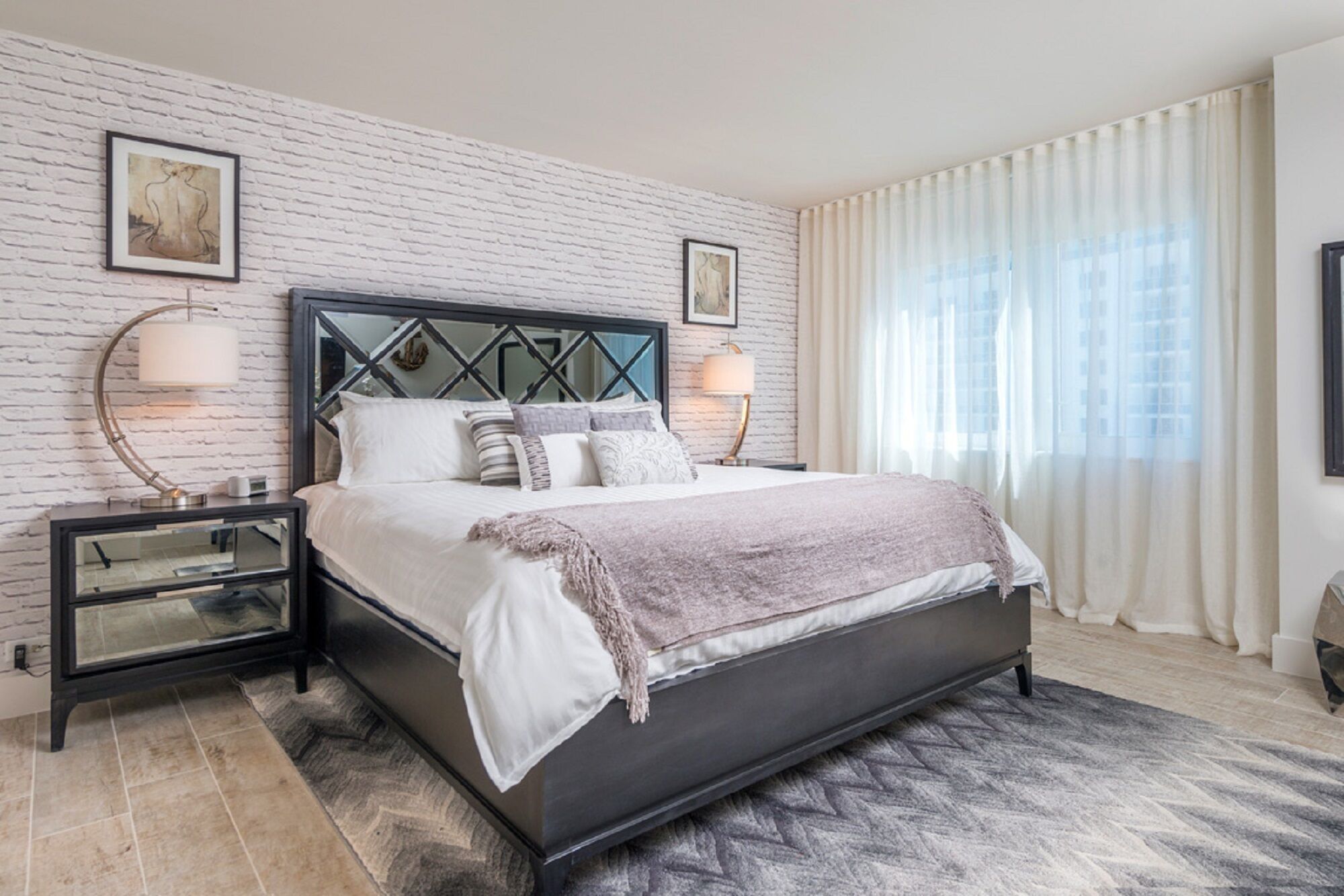 A modern bedroom with a bed, nightstands, and a large window with curtains.
