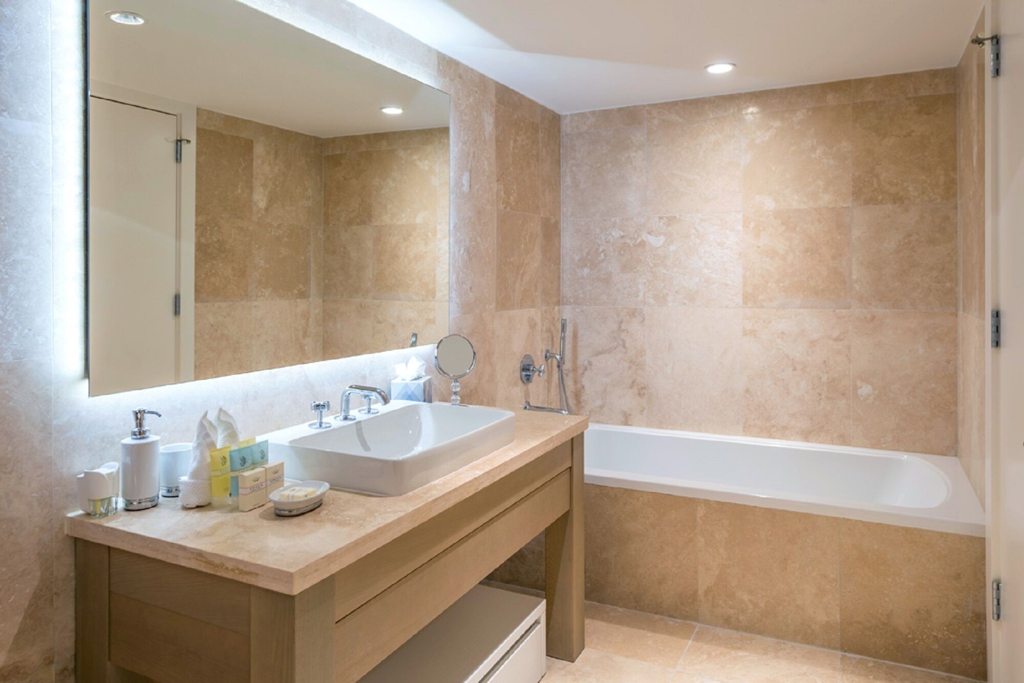 A modern bathroom with two sinks, a large mirror, and a bathtub.