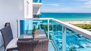 Un balcon doté d’une rambarde en verre, offrant une vue sur une plage et une piscine.
