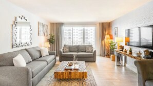 Un salon moderne avec un canapé gris, une table basse en bois et un grand téléviseur.