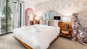Un dormitorio amplio con una cama grande, una mesita de noche de madera, un televisor y vistas al exterior.