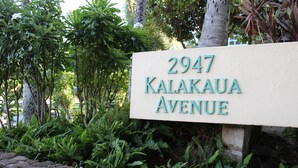 Ett gatukors med texten ”2947 Kalakaua Avenue” omgivet av frodig grönska.