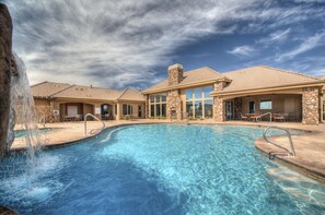 A swimming pool with a waterfall feature, stone and glass building with outdoor seating, and a clear blue sky. - Relaxing, Coral Ridge R&R! Pools Across the Street. Overlooking the Fish Pond (Washington)