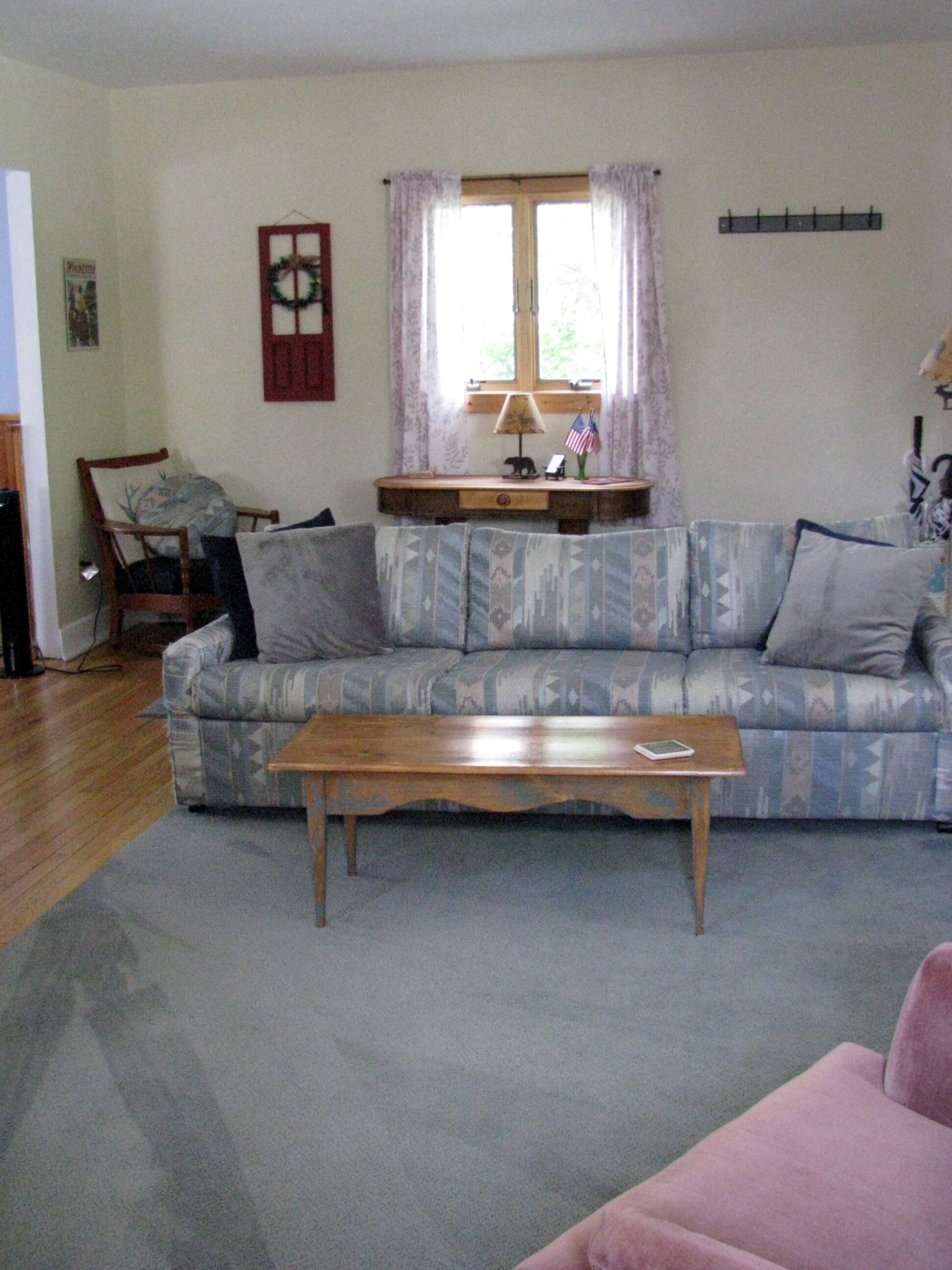A living room with a sofa, a coffee table, a lamp, and a window with curtains.