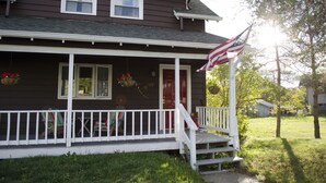 Une maison à deux étages avec un porche, une porte rouge et un drapeau américain.