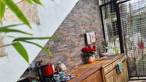 Een keuken met een houten aanrecht, een betegelde achterwand en uitzicht door een poort op een tuin.