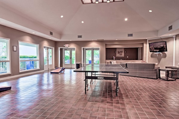 A spacious indoor area with a ping pong table, seating, and large windows.