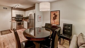 A modern kitchen with white cabinets, stainless steel appliances, and a dining area with a glass table and black chairs. - Aug/Fall/Wntr LOW RATES & 3-Nite Min.! 5Star, 10/10 Clean, comfy, quiet, secure! (Hilton Head Island)