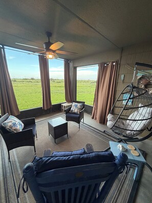 A room with a bed, a hanging chair, a table, and a view of the outdoors.