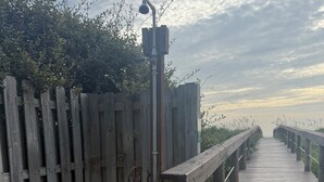 Une promenade en bois, dotée d’une rambarde métallique, qui mène à un plan d’eau.