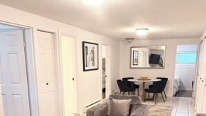 Un salon moderne avec une table basse blanche, un canapé gris et un coin repas comprenant une table et des chaises.