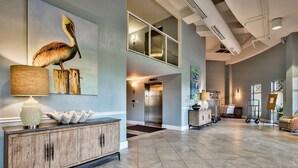 A spacious lobby with a wooden cabinet, a large painting of a bird, and a modern elevator.