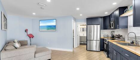 Una cocina moderna con armarios oscuros, un refrigerador de acero inoxidable y una encimera de madera.