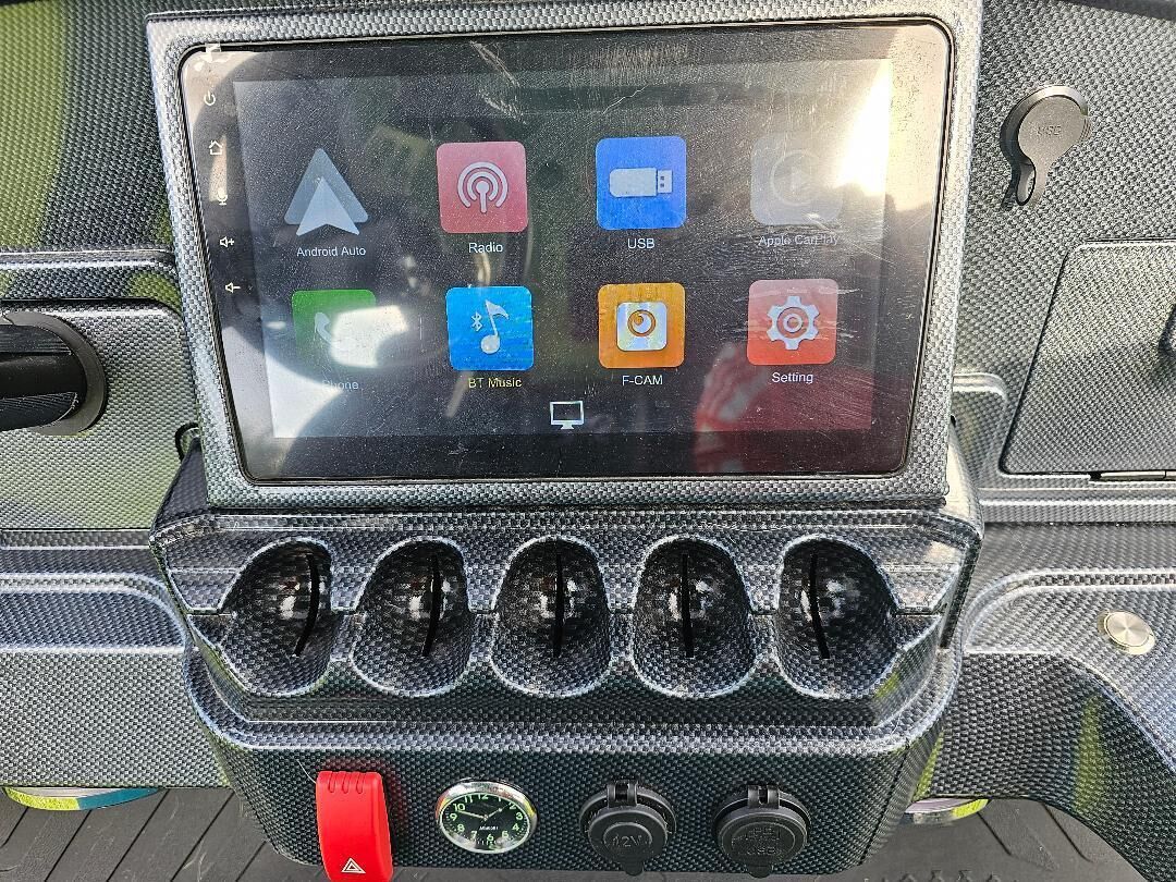 Ein Autodashboard mit einem Touchscreen-Display und einer Carbonfaser-Verkleidung.