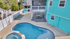 A swimming pool with a hot tub, lounge chairs, and a deck area.