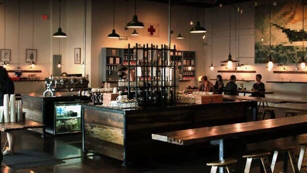 Un'accogliente area bar con tavoli in legno e lampade a sospensione.