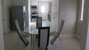 A modern kitchen with stainless steel appliances, a glass dining table, and contemporary chairs. - A house in the historic bishop's art district (Dallas)