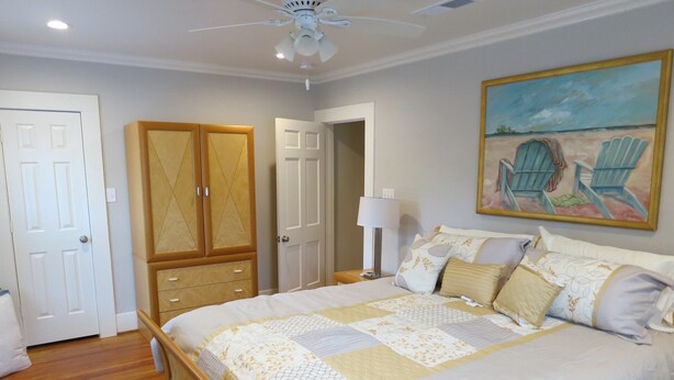 A bedroom with a bed, wardrobe, and a painting of chairs on the wall. - A house in the historic bishop's art district (Dallas)