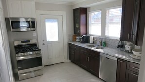 A modern kitchen with stainless steel appliances, dark wooden cabinets, and a white door. - A house in the historic bishop's art district (Dallas)