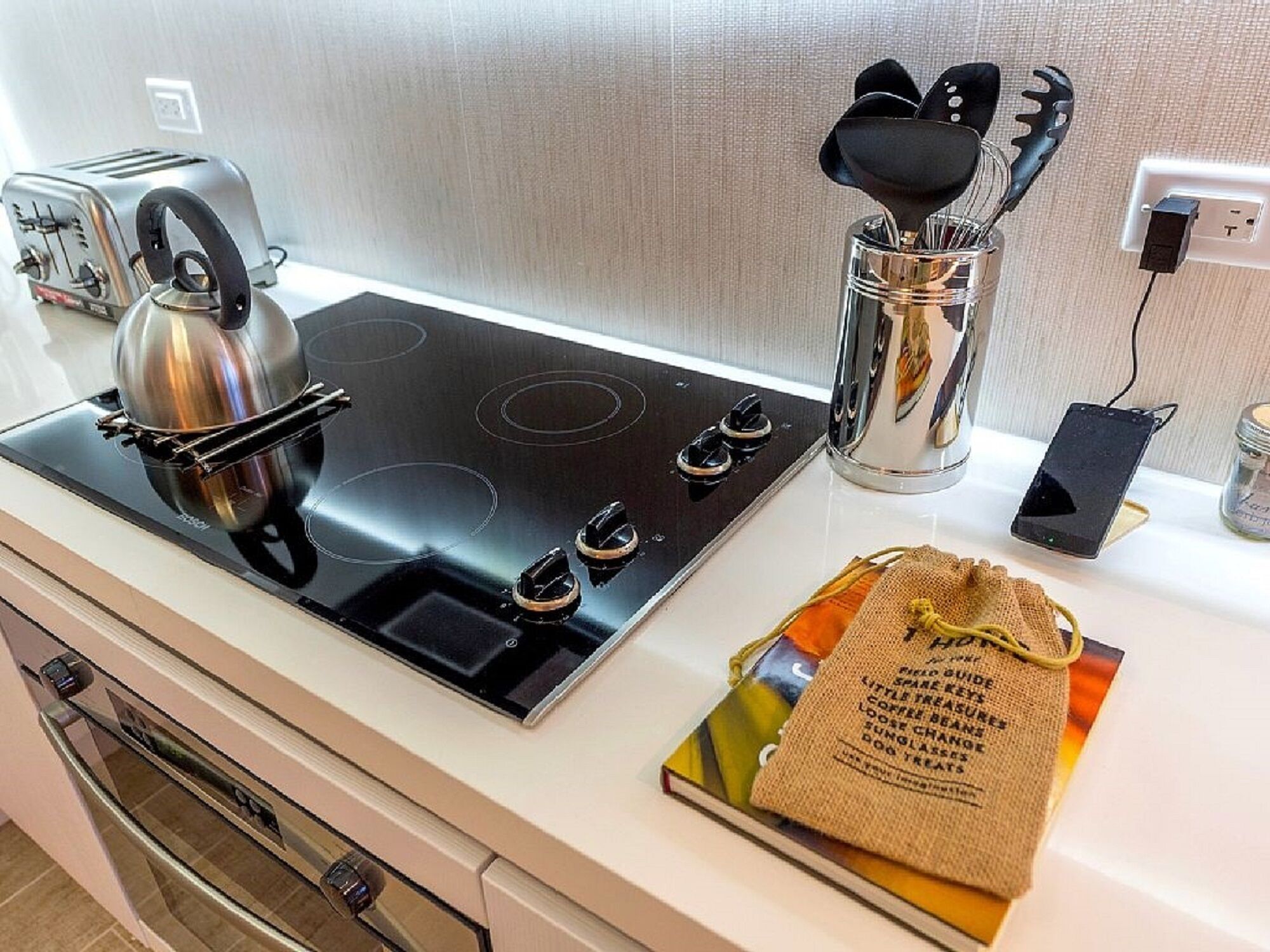 A kitchen with a black stovetop, a toaster, a coffee maker, and a bag of coffee beans.