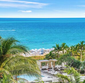 A resort with a pool, lounge chairs, and a beach area with umbrellas.
