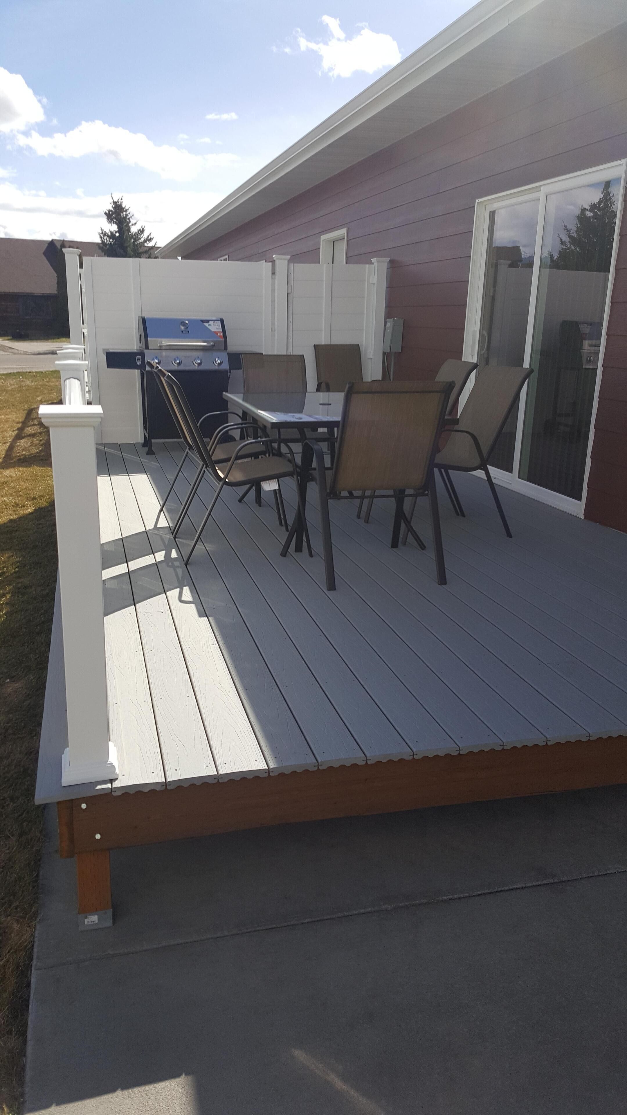 Une terrasse extérieure avec un barbecue, des chaises et une table.