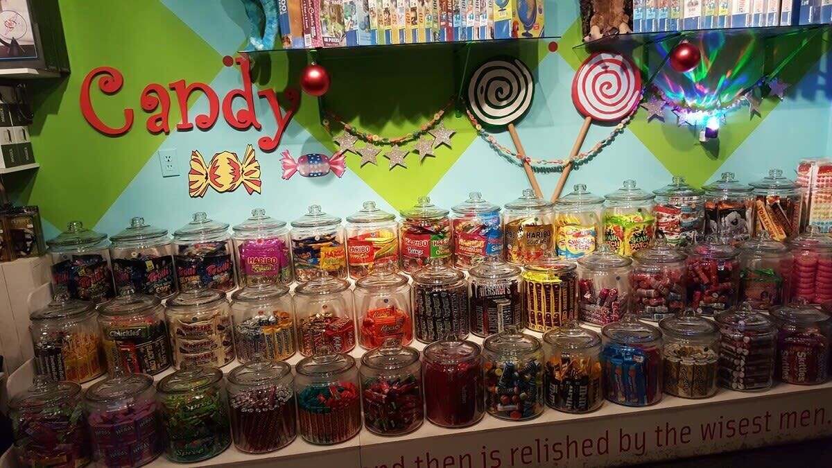 Un présentoir à bonbons avec différents pots remplis de friandises et une pancarte indiquant « Bonbons ».