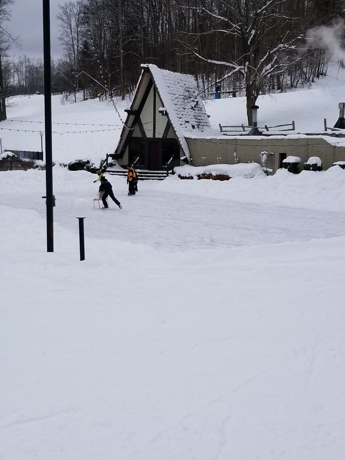A snow-covered landscape with a small building and a tree.
