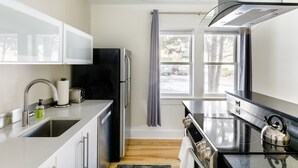 Una cocina moderna con electrodomésticos de acero inoxidable, horno empotrado y ventana con cortinas.