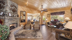 A cozy wooden interior with a stone fireplace, comfortable seating, and a view of the outdoors. - Quaint Cabin With Spectacular Views Of The Granite Dells, Great Hiking/Kayaking! (Prescott)