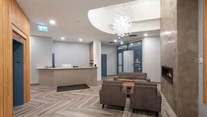 A modern lobby with a reception desk, seating area, and a fireplace. - Village Modernist Studio - Hottub & Pool (Whistler)