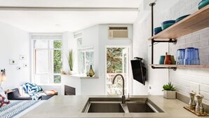 A modern kitchen with a large island, double sink, and a built-in TV. - Village Modernist Studio - Hottub & Pool (Whistler)