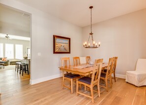 A dining area with a wooden table and chairs, a chandelier, and a framed picture on the wall.